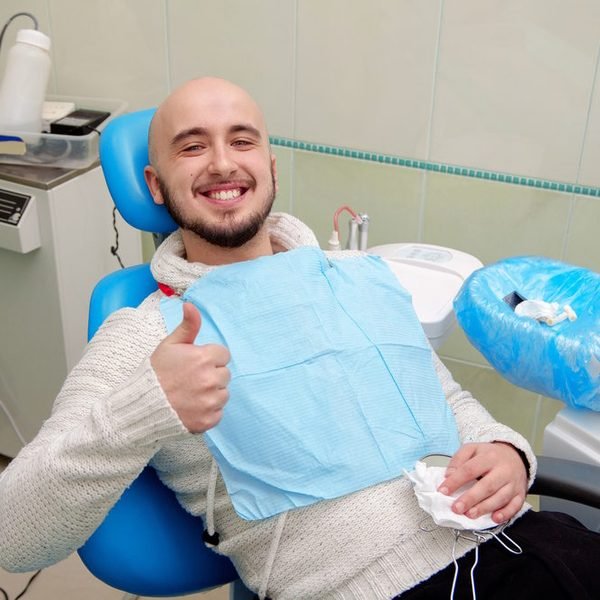 Ein Patient zeigt im Behandlungsstuhl den Daumen nach oben